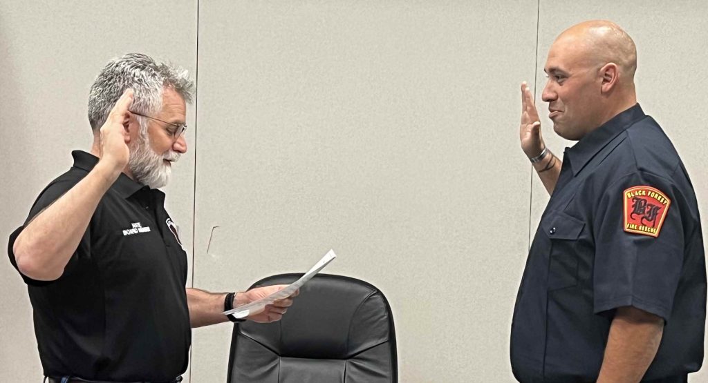 From left, Chair Nate Dowden administers the oath of office to the new Training Capt. Michael Torres at the beginning of the Sept. 20 Board of Directors meeting. Family members pinned on the badge and lapel pins during the ceremony. Photo by Natalie Barszcz.