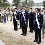 The skies were gloomy, befitting the somber occasion, as a few hundred people attended the Memorial Day ceremony in Monument Cemetery on May 26. The rain held off as local and state officials spoke and the names of veterans buried in the 5 acres of land were read aloud, each name followed by the ringing of a bell. The ceremony ended with the playing of taps by Michael Carlson on his bugle. This is Carlson’s last year performing at the ceremony. He’ll be attending college in South Dakota next Memorial Day. Above: Members of VFW Post 7829, American Legion/Tri-Lakes Post 9-11, Boy Scout Troop 17, and others salute the flags. Photo by Michael Weinfeld. See video clips below.