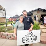 Above: The Tri-Lakes Chamber of Commerce hosted a ribbon-cutting ceremony on July 1 for Routes Outfitter. Routes continues to have beer and whisky on tap for visitors, just as the previously-named Trails End Taproom provided, but the space is now mostly dedicated to outdoor gear and rentals and bike repair. In photo, Routes Outfitter owners Kristin and Jason Mezey. Photo by Chris Jeub.